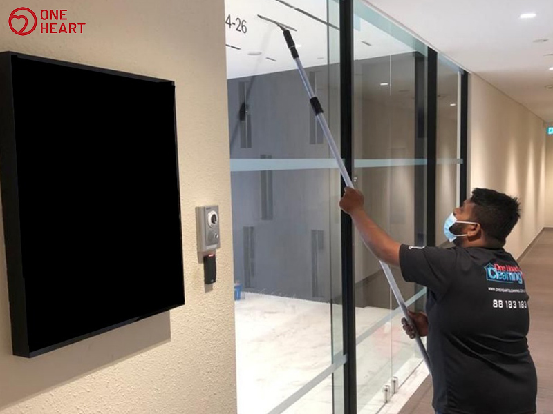 a professional cleaner cleaning glass office door for disinfection